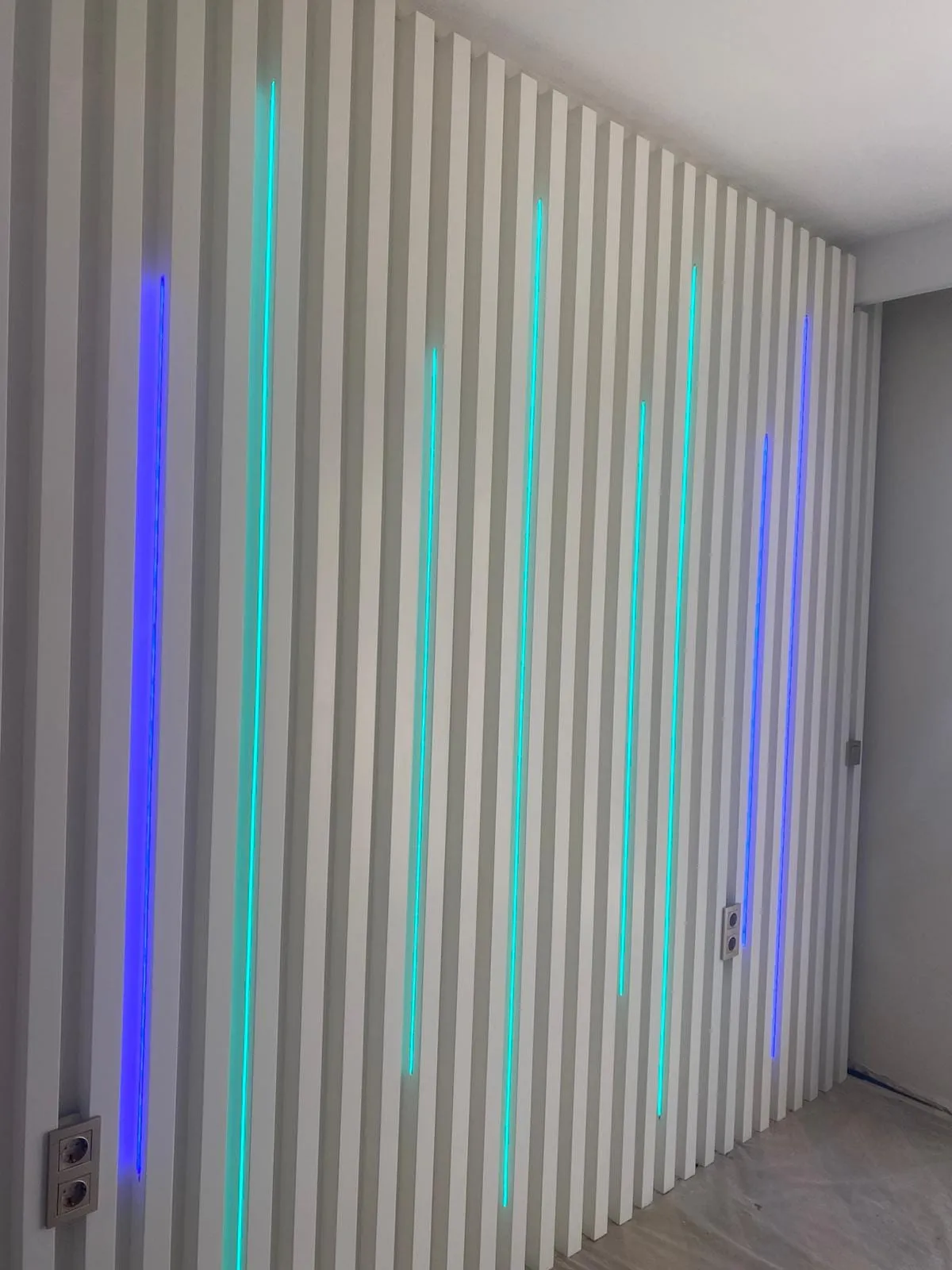 Ahşap lamelli duvar paneli arkasına gizlenmiş renkli LED aydınlatma